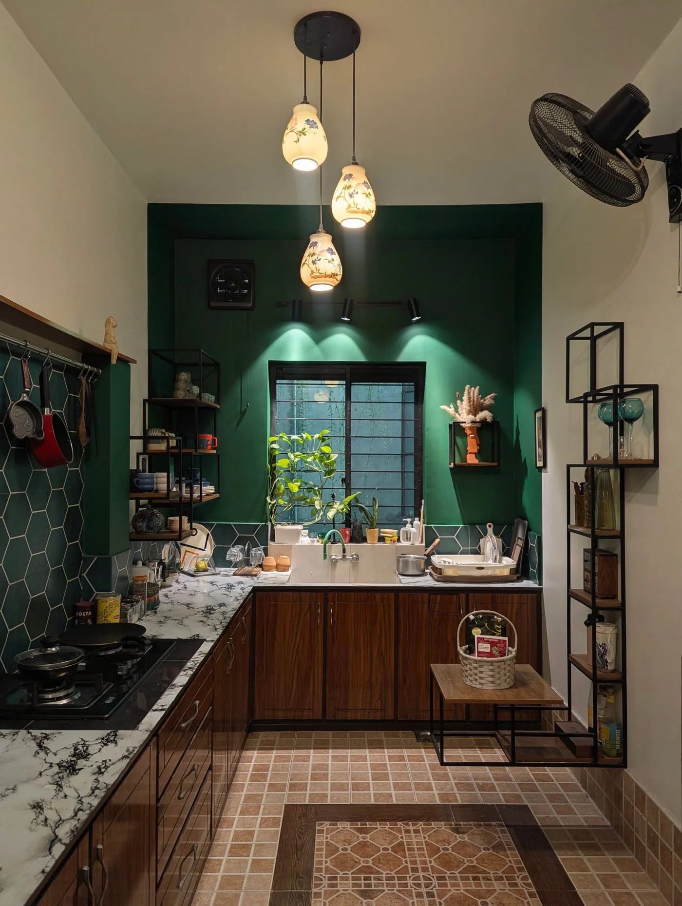 Cozy modern kitchen featuring marble countertops, wooden cabinets, and artistic lighting.