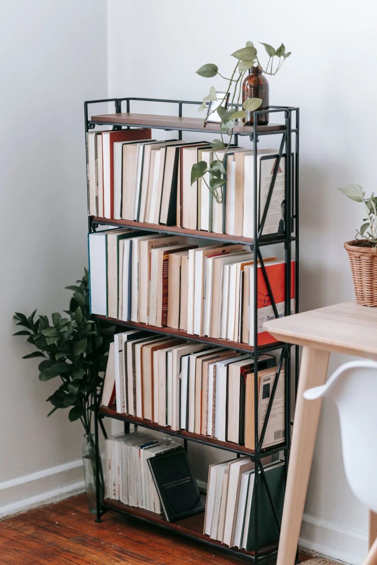 Open bookcase with books, plants and a wooden desk