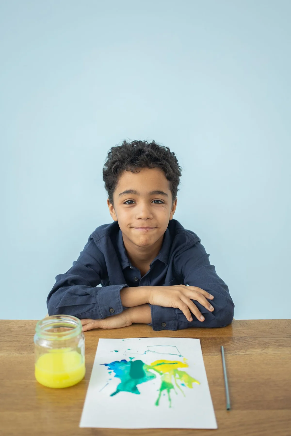 Child seated at a table with a colourful painting