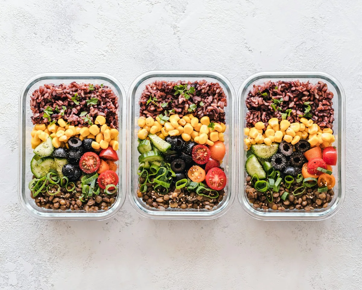 Three prepared food containers arranged on a pale surface