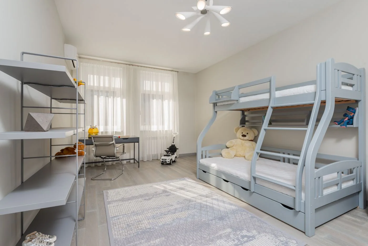 Bright room with bunk beds, open shelves and a desk