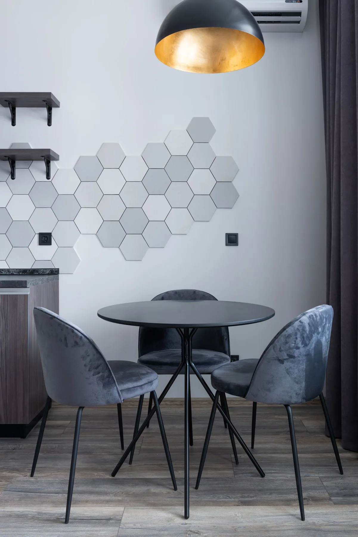 Small round black dining table with chairs beneath a pendant lamp