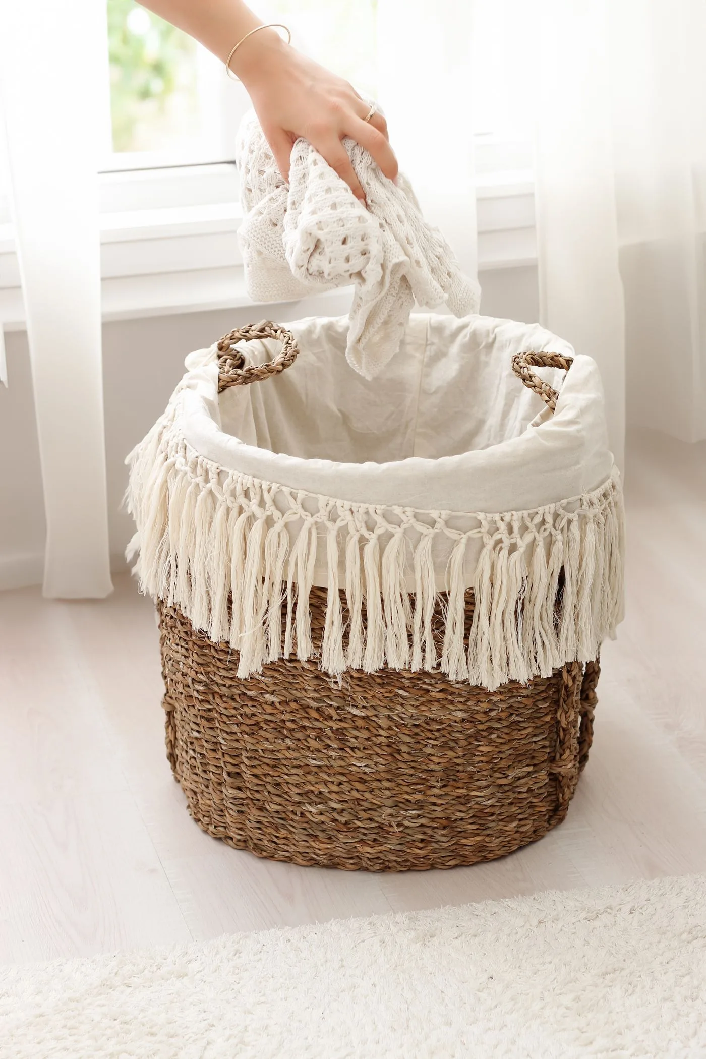 A woven basket with a pale fabric liner and decorative fringe