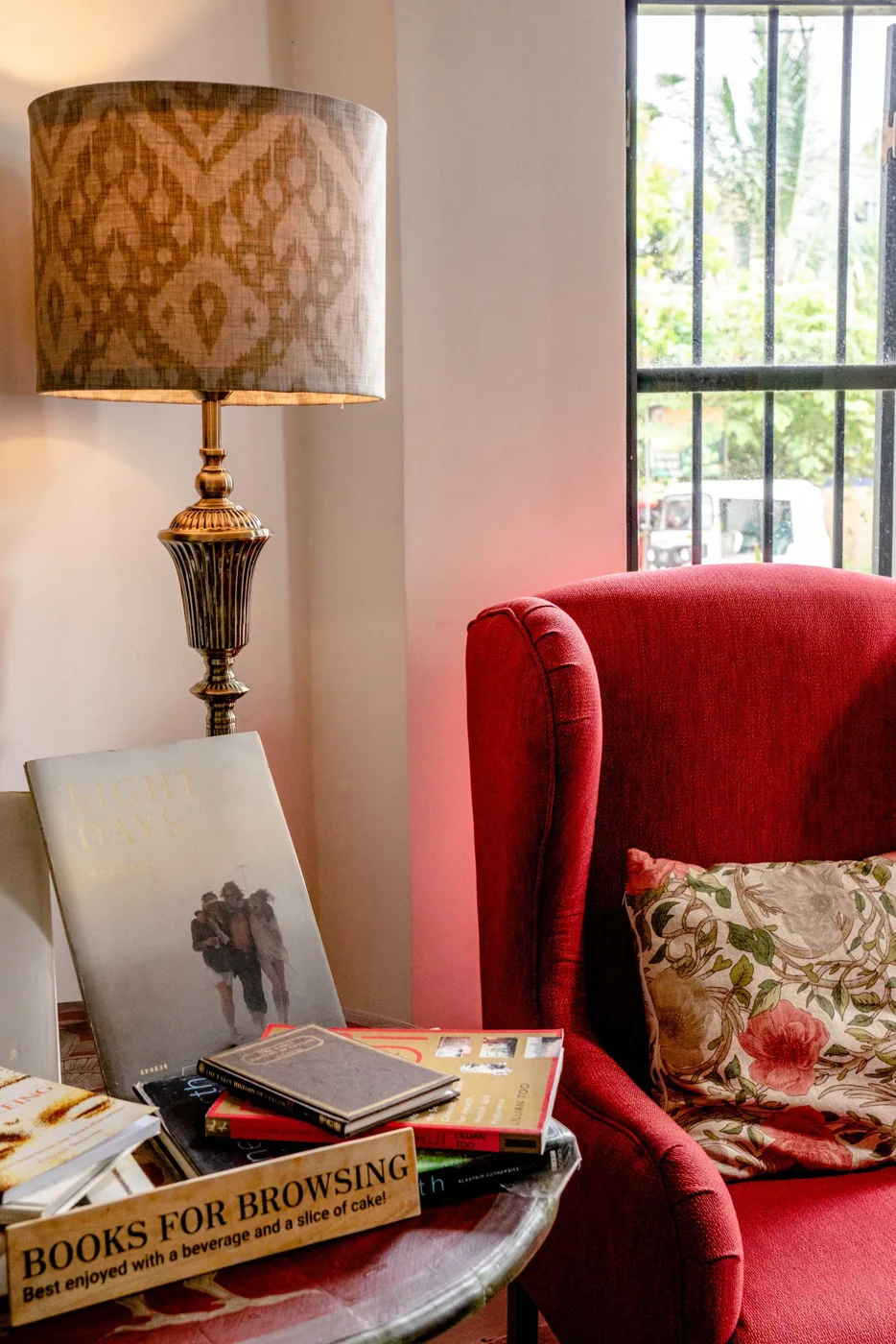 A red chair beside a lamp and a framed picture