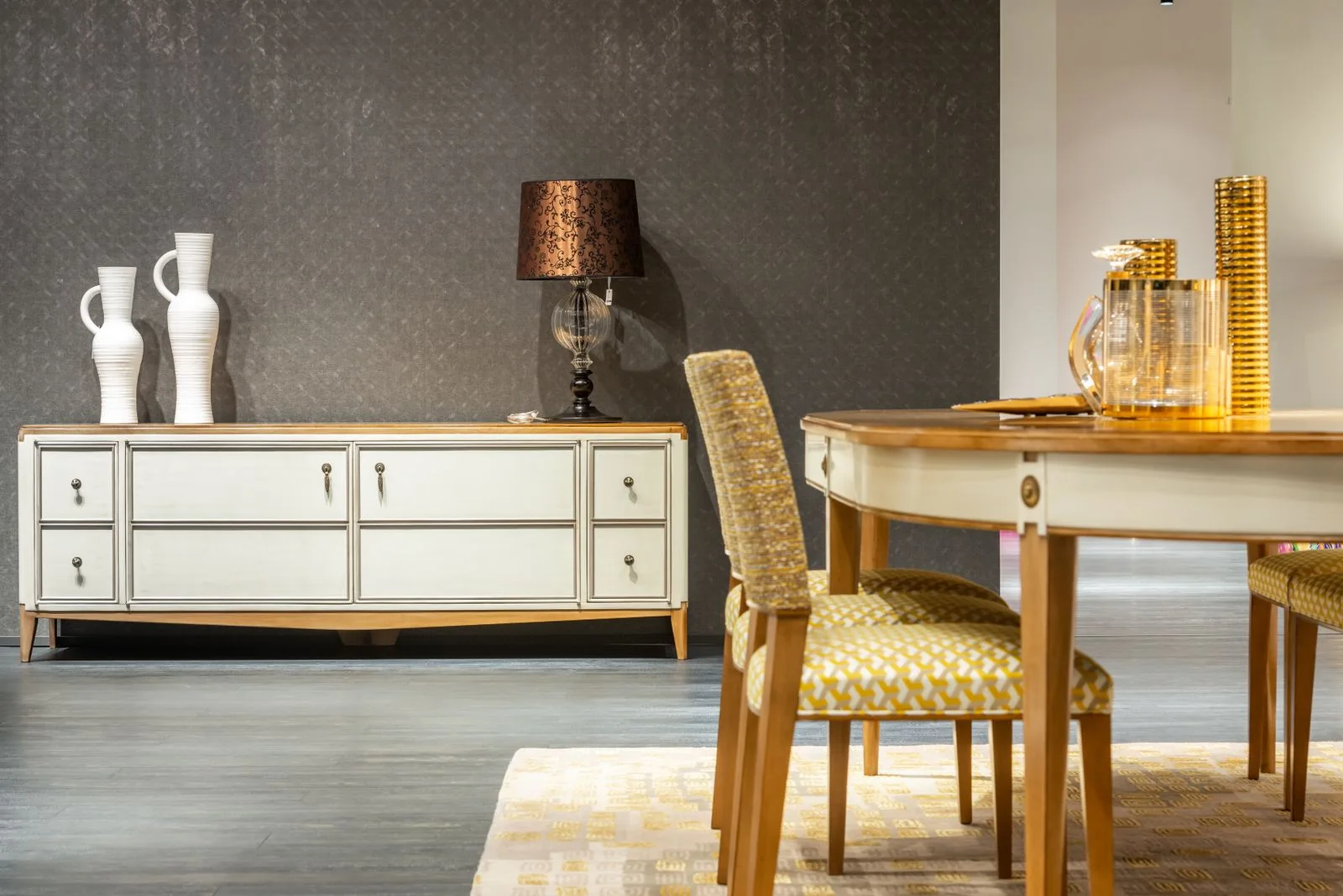 A dining area with an upholstered chair, table and sideboard